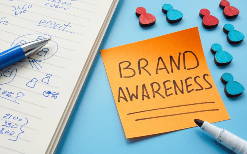 A close-up of a laptop keyboard with a hand typing, and a smartphone resting nearby.