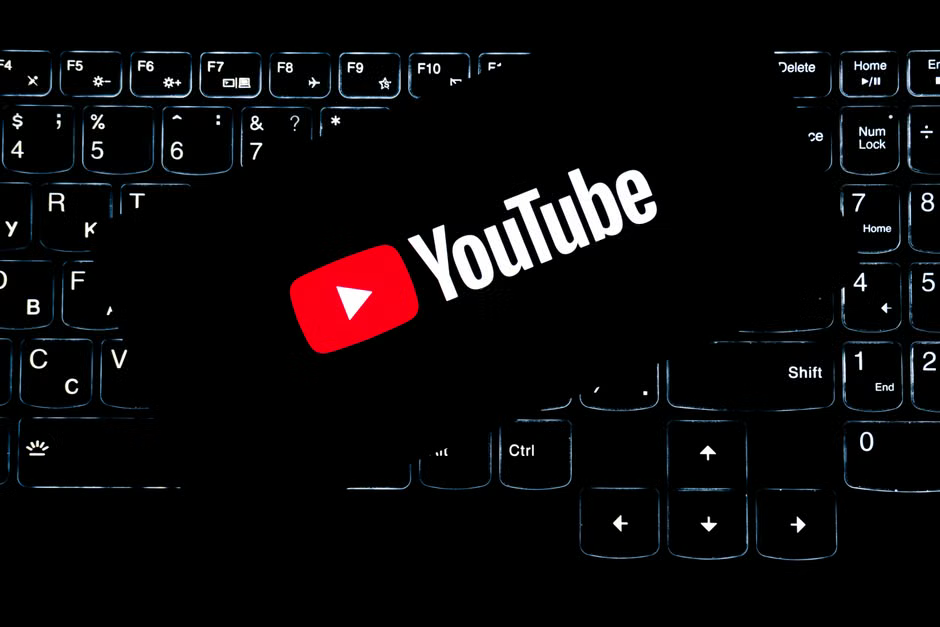 The YouTube logo, a red play button icon, on a black computer keyboard with backlighting.