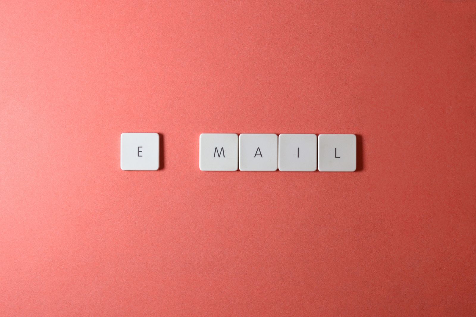 Keyboard letter tiles spelling the word email on a coral background